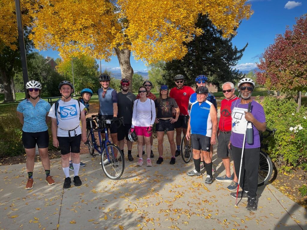 Group smiling at CCB in front of tree with yellow leaves